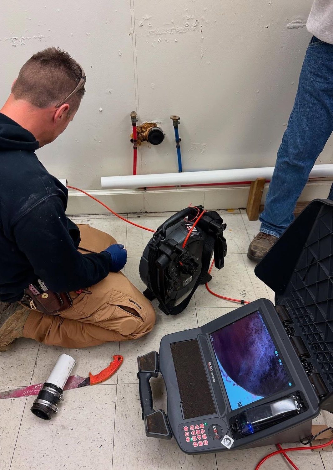 Technician running a drain camera while the homeowner watches the monitor