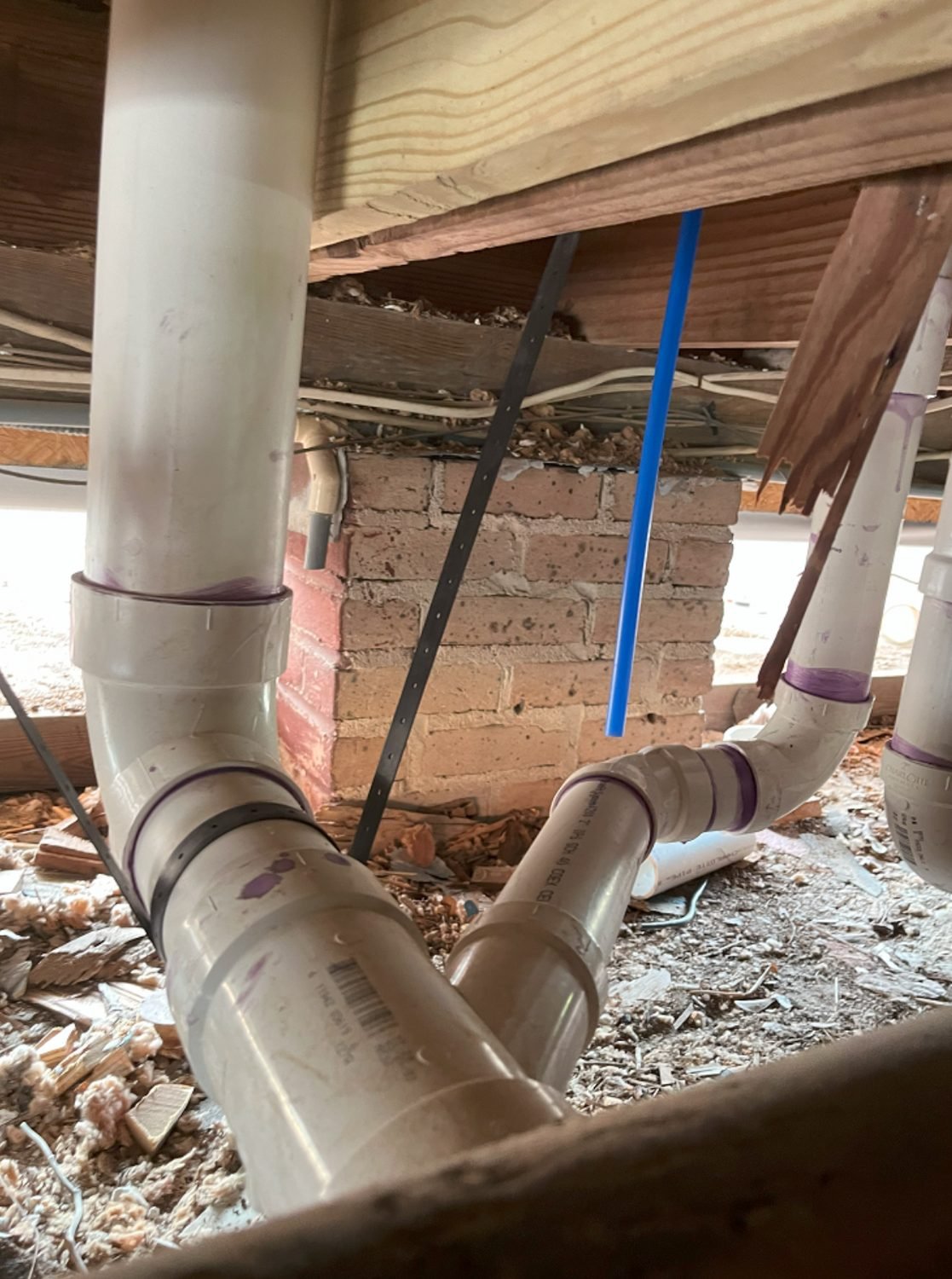 New drain and vent piping run under a floor in a crawlspace