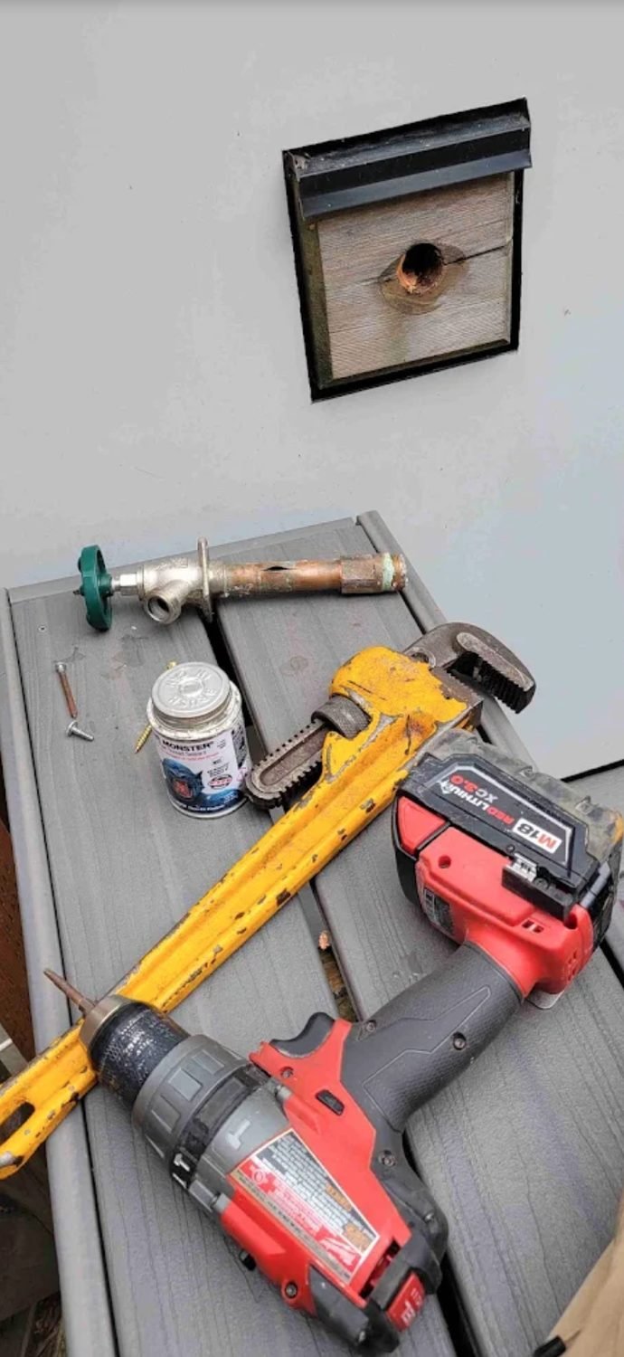 Corroded hose bib removed and laid out with tools on a deck