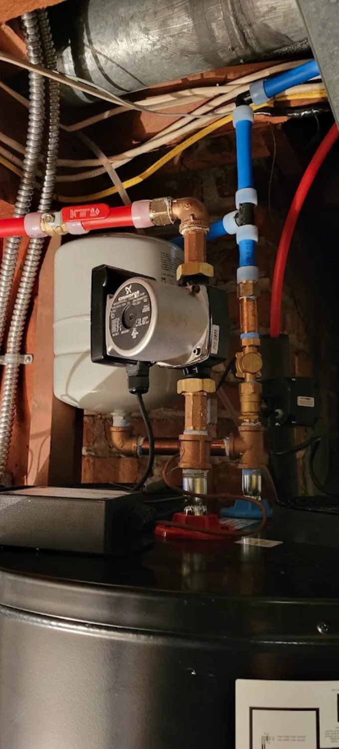 Copper manifold, valves and recirculation pump in a mechanical room