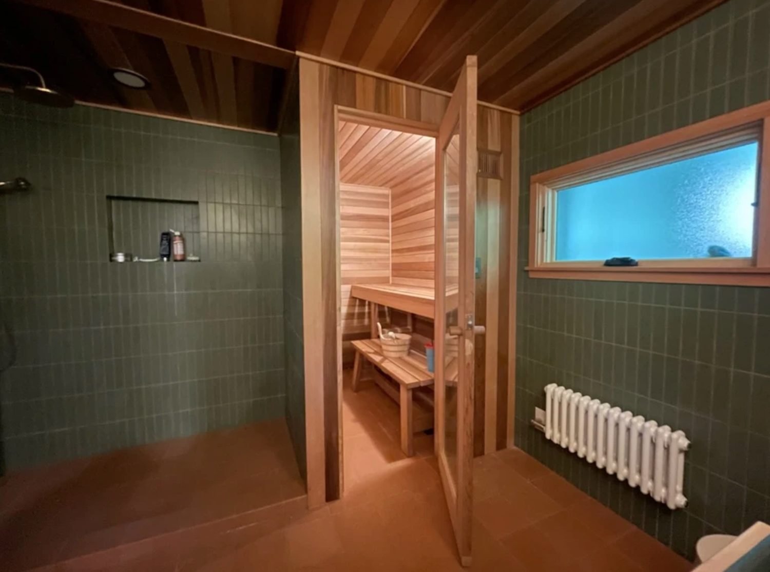 Finished bathroom with a tiled shower area beside a cedar sauna