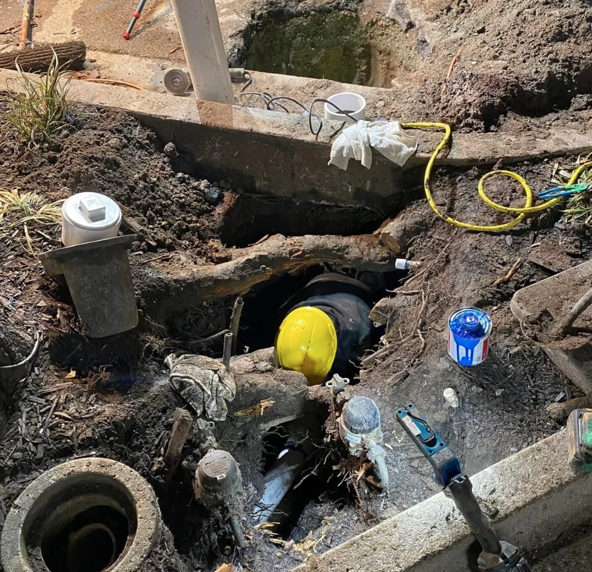Night trench work exposing sewer pipe and cleanouts