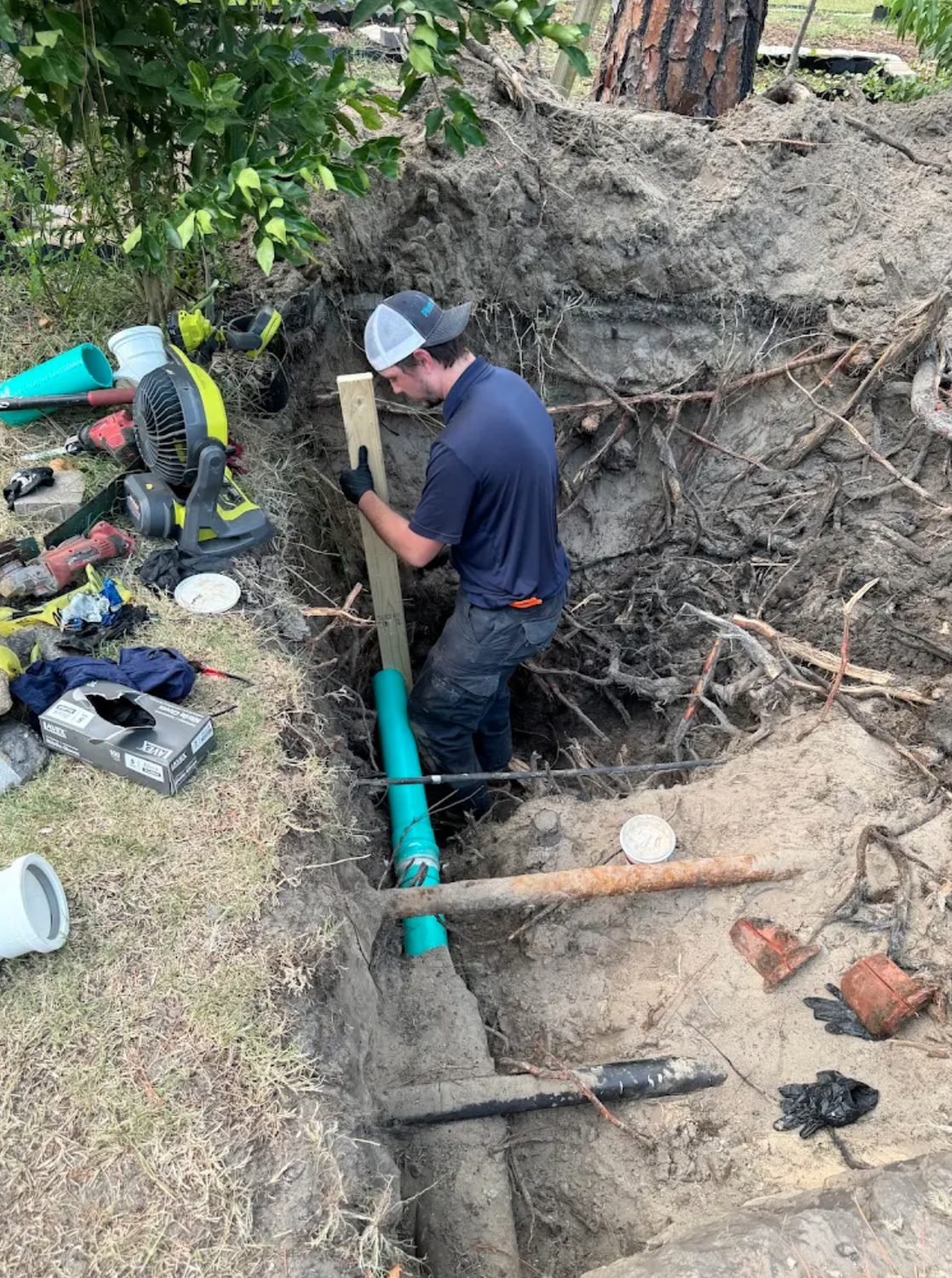Technician in a trench setting new sewer pipe where old clay pipe was removed