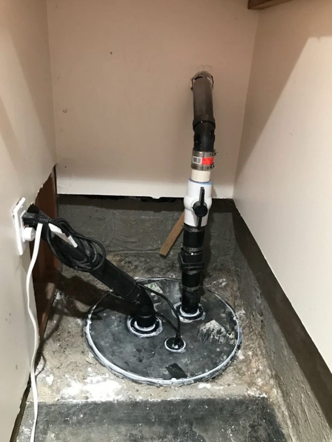 Sump pump installed in a basement pit with discharge piping