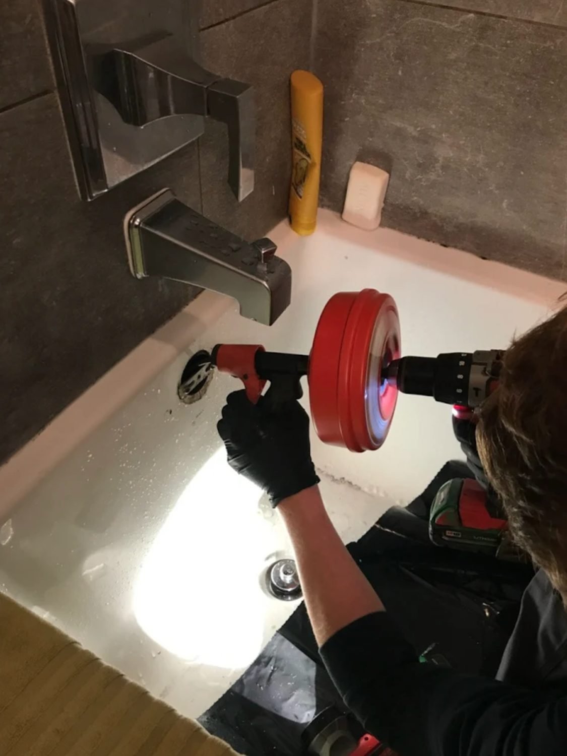Technician running a drain machine at a bathtub