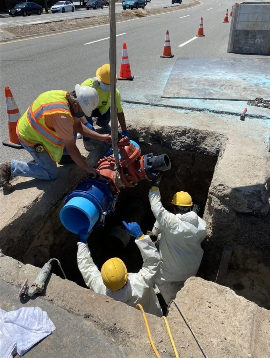 Crew setting a valve assembly into a shored excavation